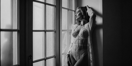 A mysterious woman standing in front of a window wearing lace lingerie under moonlight.