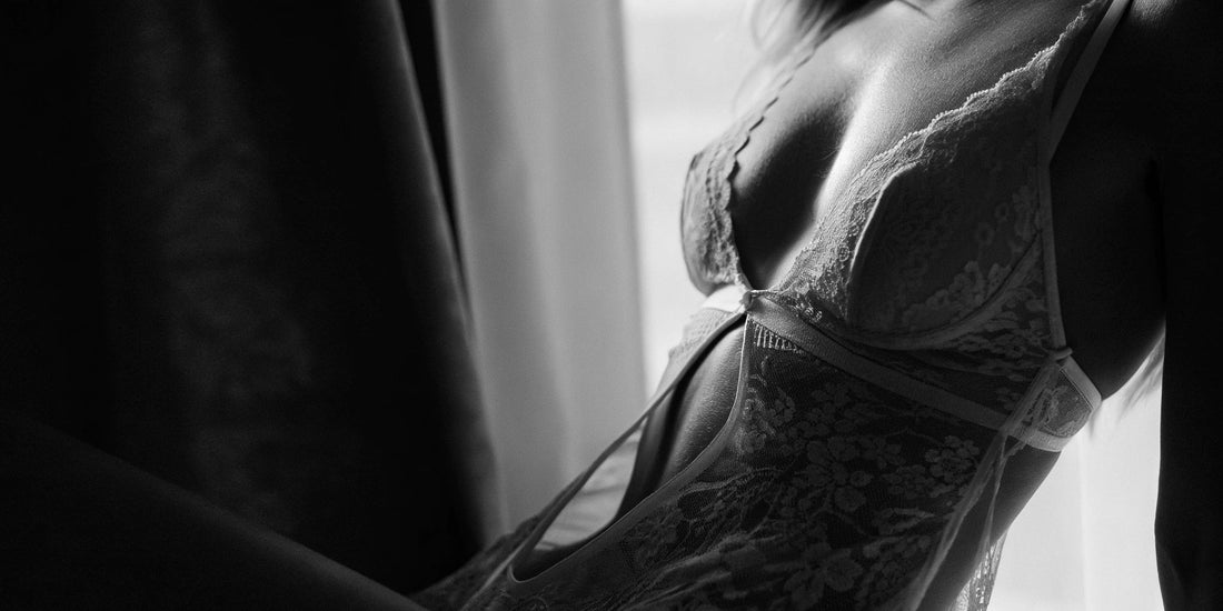 Black and white close-up of a woman in lace lingerie, softly lit, showing the texture of fabric and skin in a luxurious, seductive tone.